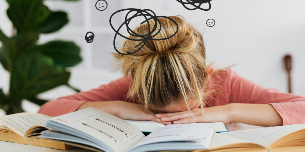 Woman with her head on her desk and open notebooks symbolising a lifestyle freelance writer